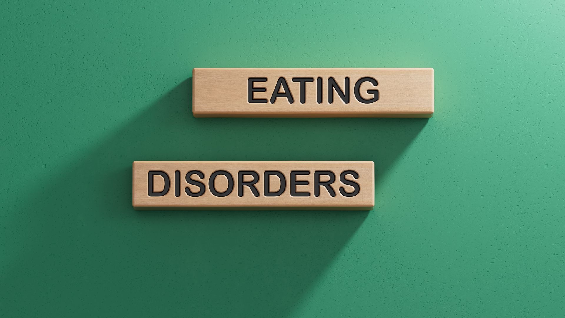 Wooden blocks spelling “EATING DISORDERS” on a green background.