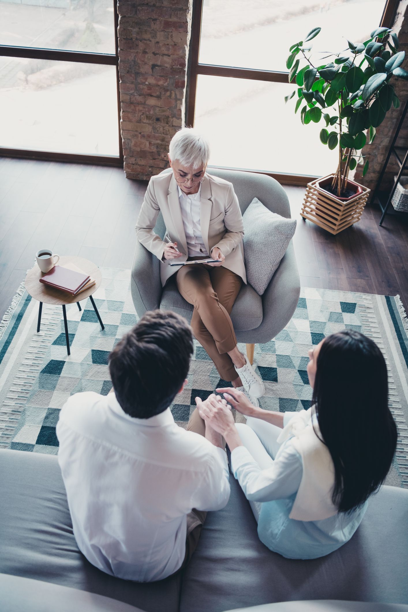 Three people seated in a bright living room, chatting with an older woman in an armchair.