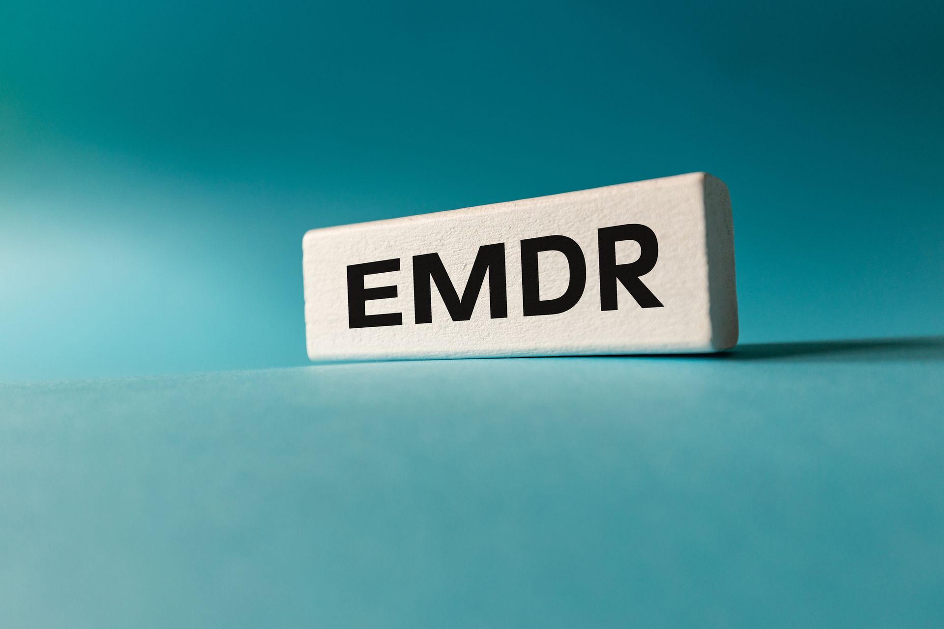 EMDR letters on a white block against a teal background