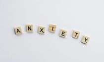 Wooden letter tiles spelling “ANXIETY” on a white background.
