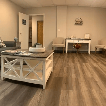 Cozy living room with beige chairs, white coffee table, wood flooring, and a small desk against the wall