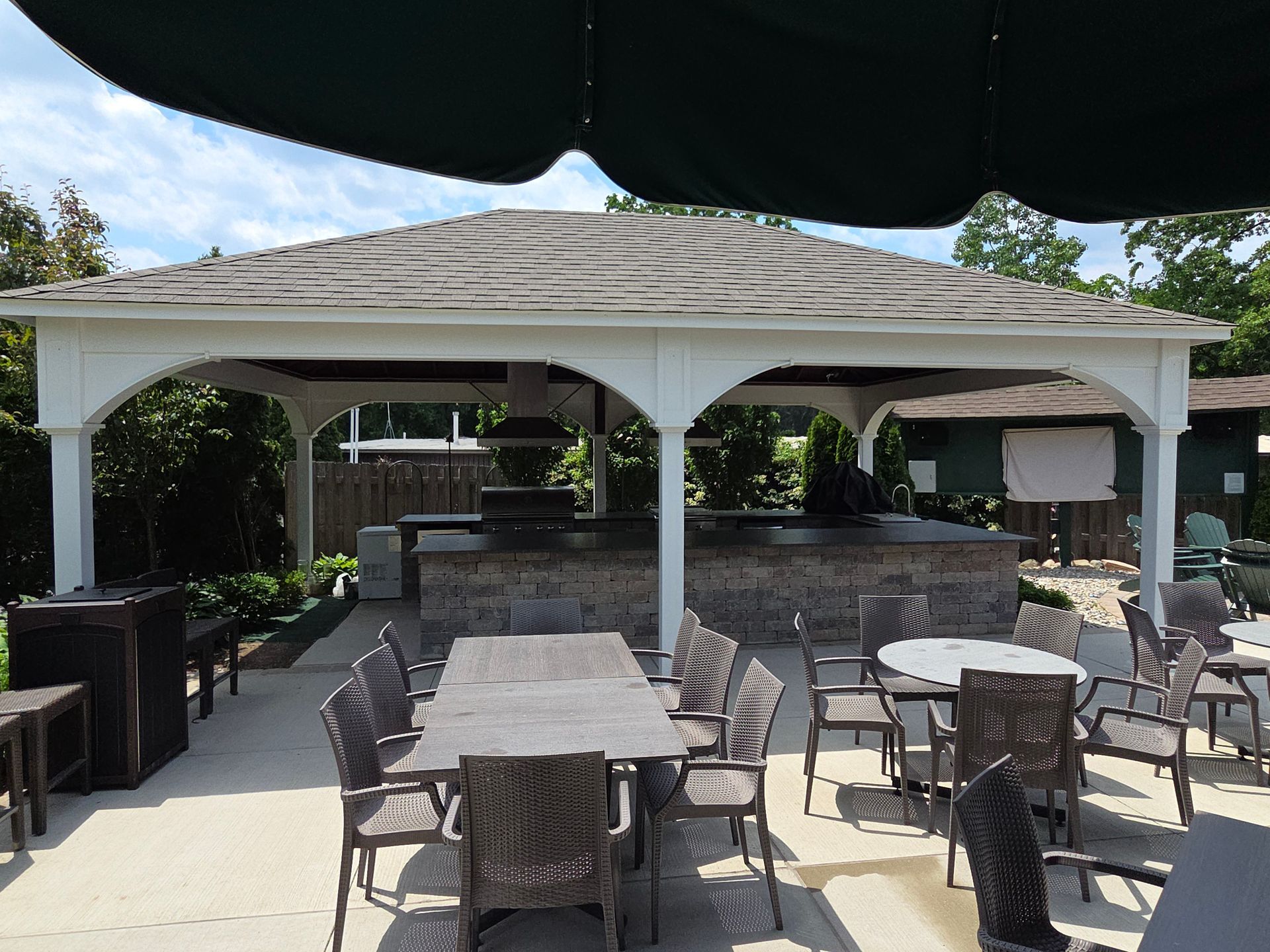 Outdoor patio with tables and chairs under a white canopy beside a bar area