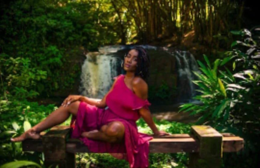 Sitting relaxed on a bench in front of the waterfall in the mauve dress