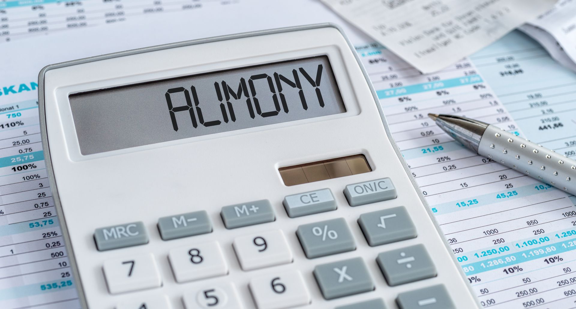 A white calculator with the word ALIMONY displayed on its screen, resting on financial documents next to a metal pen.