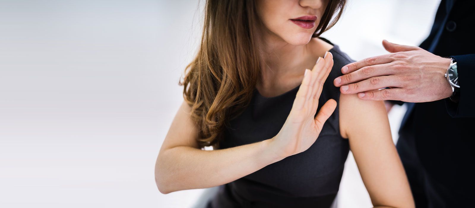A person uses a hand gesture to signal no while another person places a hand on their shoulder.