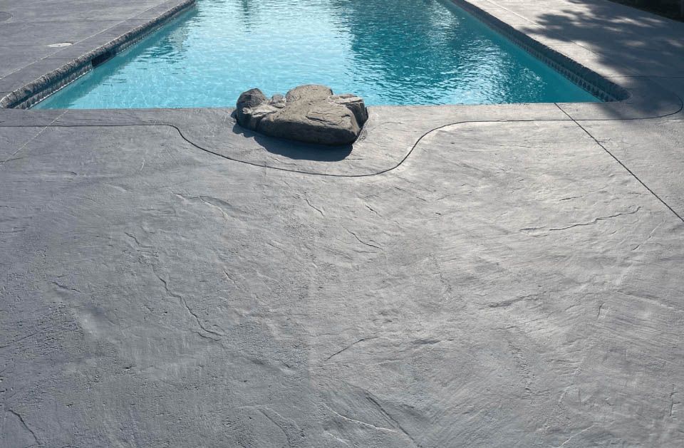 A large rock is sitting on the edge of a swimming pool.