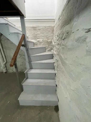 A set of stairs in a basement next to a brick wall.