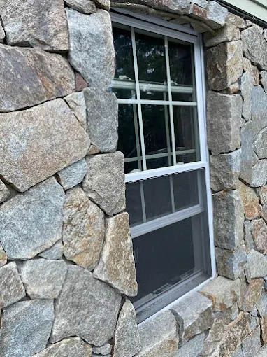 A stone wall with a window in the middle of it.