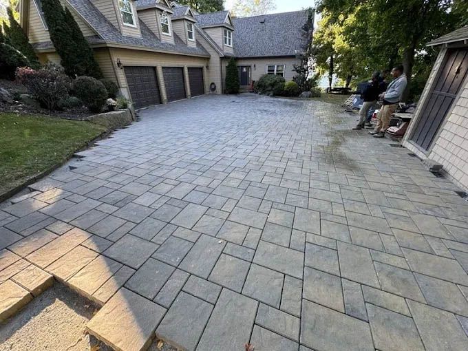 A brick driveway is being built in front of a large house.