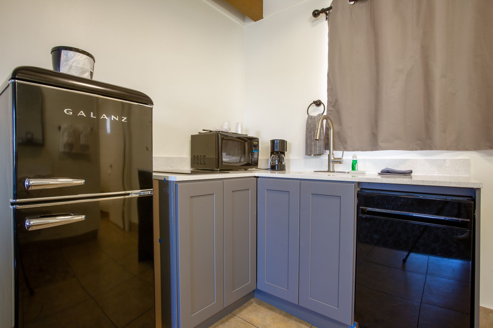 Modern kitchenette at Dreamcatcher Inn Sedona with black refrigerator, gray cabinets, and black dishwasher