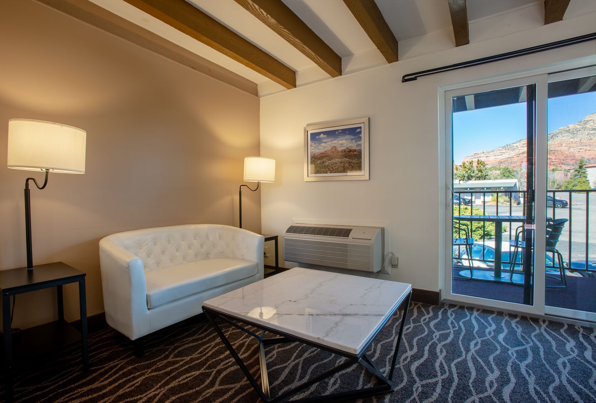 Cozy living area at Dreamcatcher Inn Sedona with couch, table, lamp, and sliding glass doors to scenic views