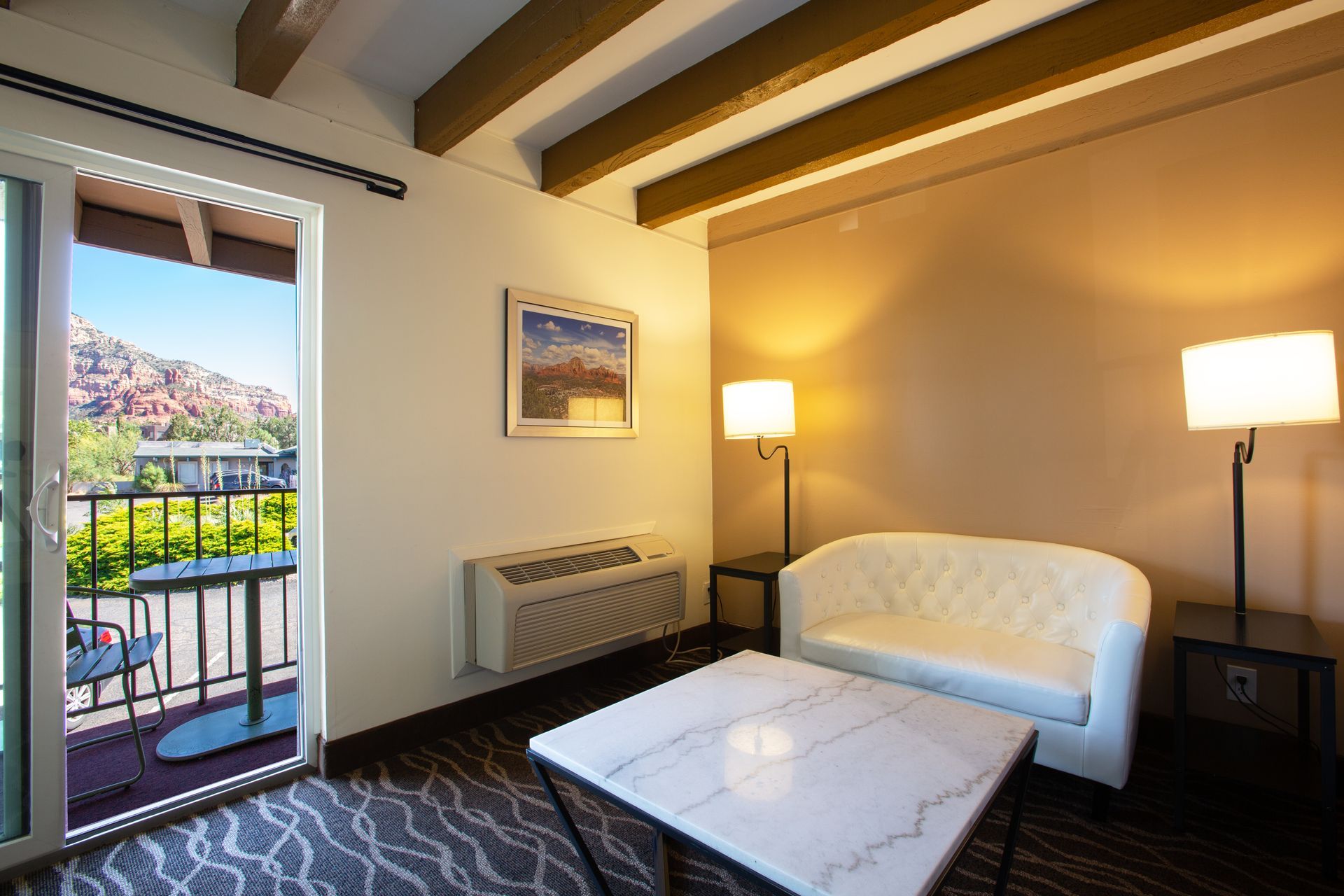 Dreamcatcher Inn Sedona hotel room with couch, chair, table, and private balcony with scenic views