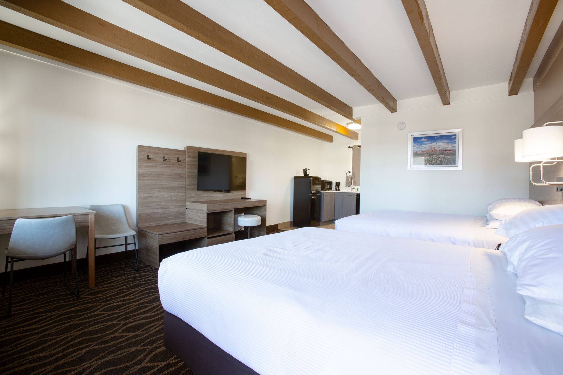 Dreamcatcher Inn Sedona hotel room with two beds, a work desk, and a flat-screen TV