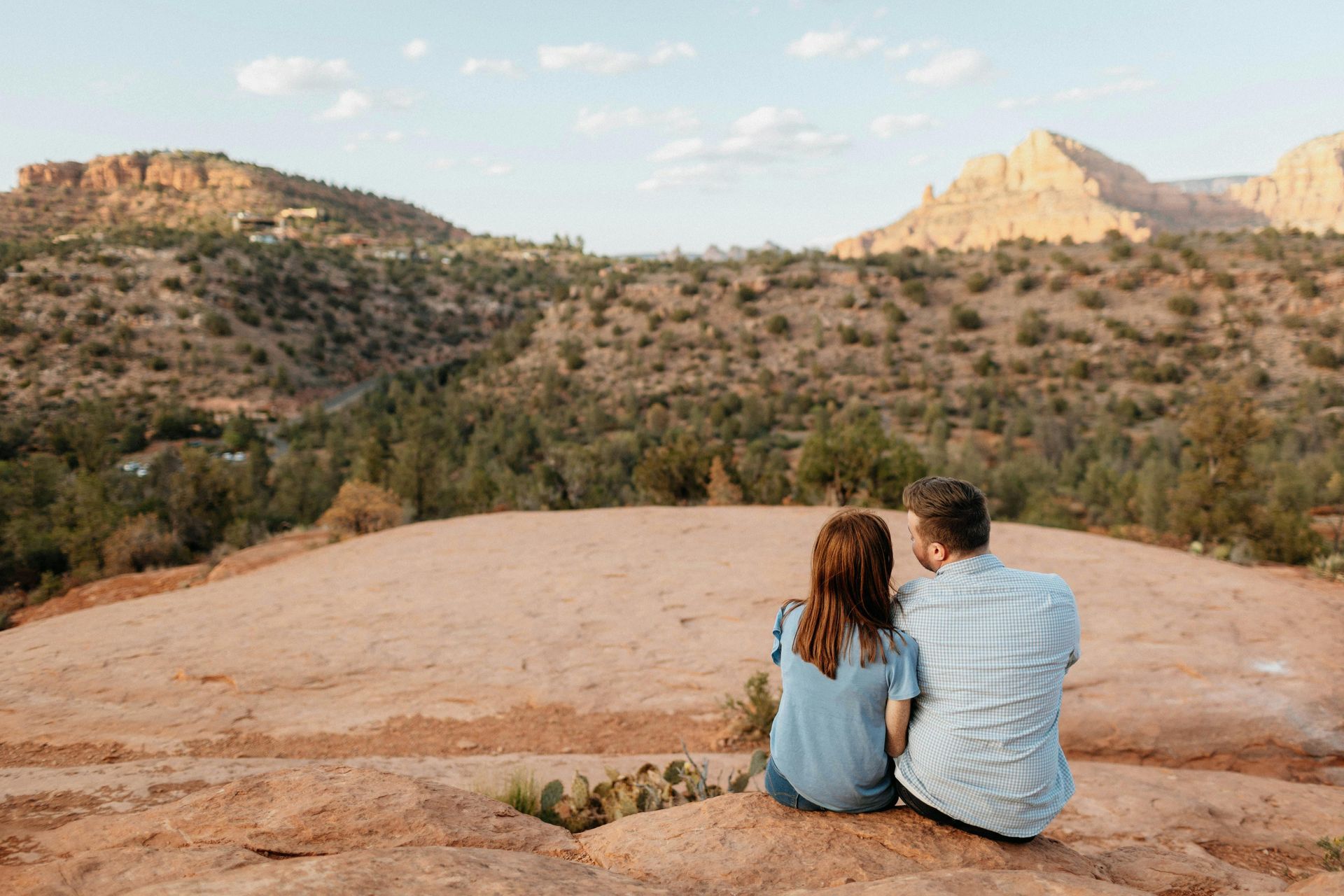 Couple sitting on rocky cliff with panoramic Sedona valley views near Dreamcatcher Inn