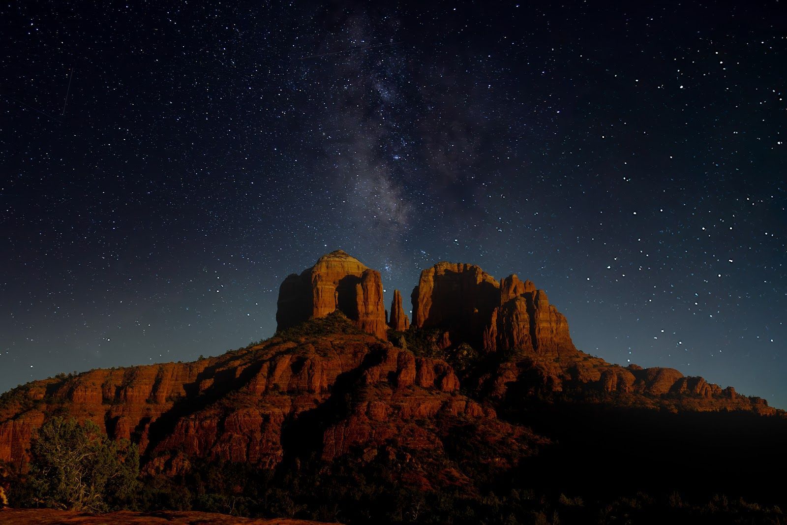 Dark desert sky and the Milky Way over red rock silhouettes near Sedona at night