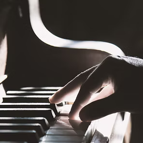 Hand playing piano keys in dramatic black-and-white lighting