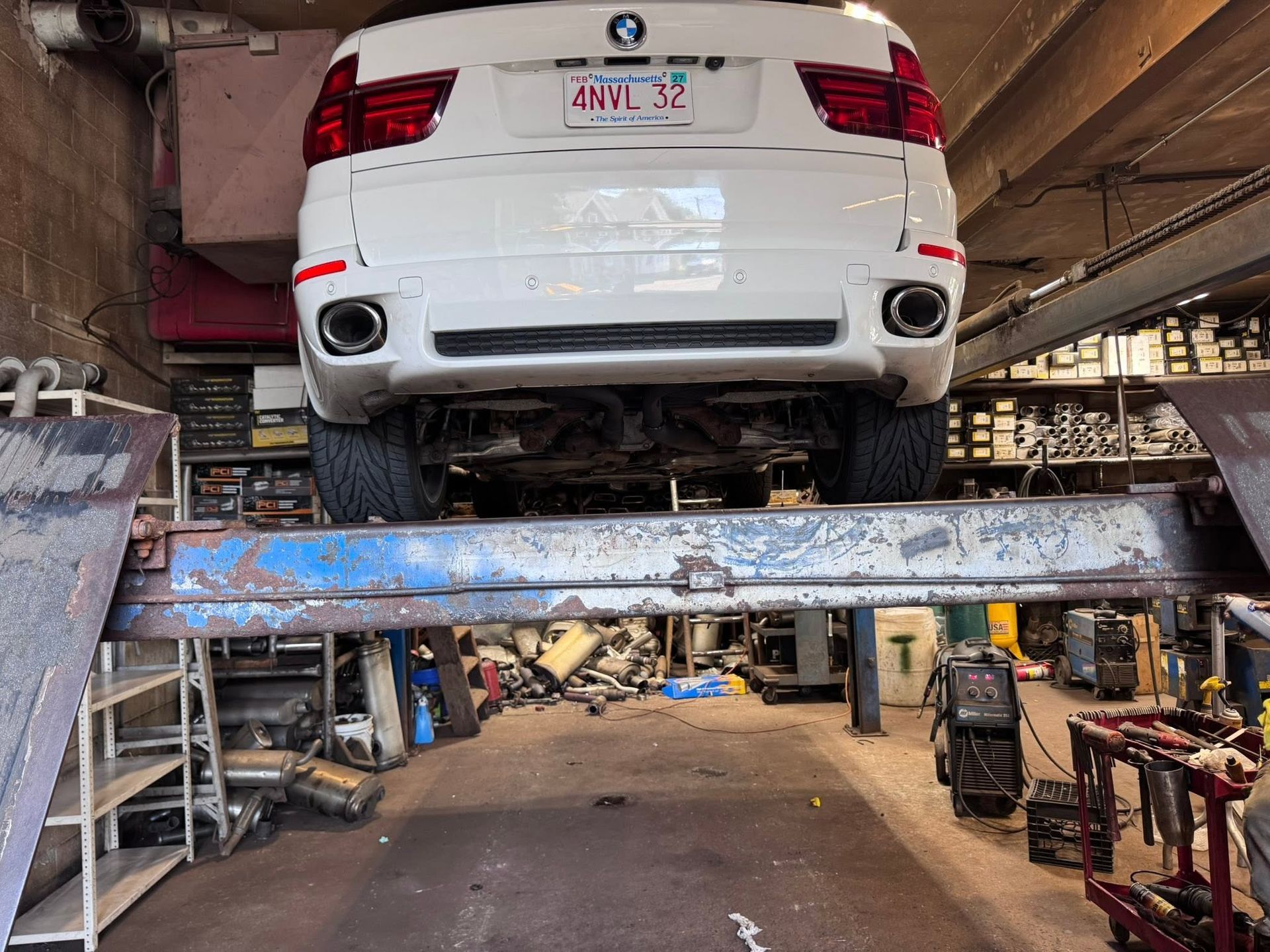 White car raised on a lift in an auto repair garage