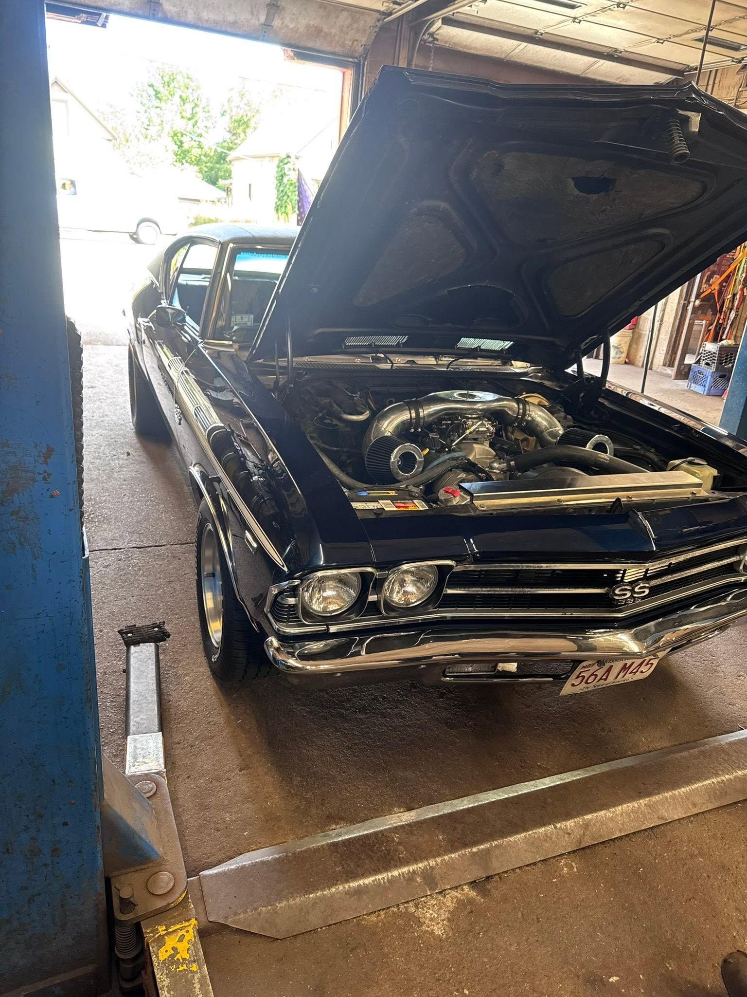 Classic black car with hood open in a garage, showing the engine bay.