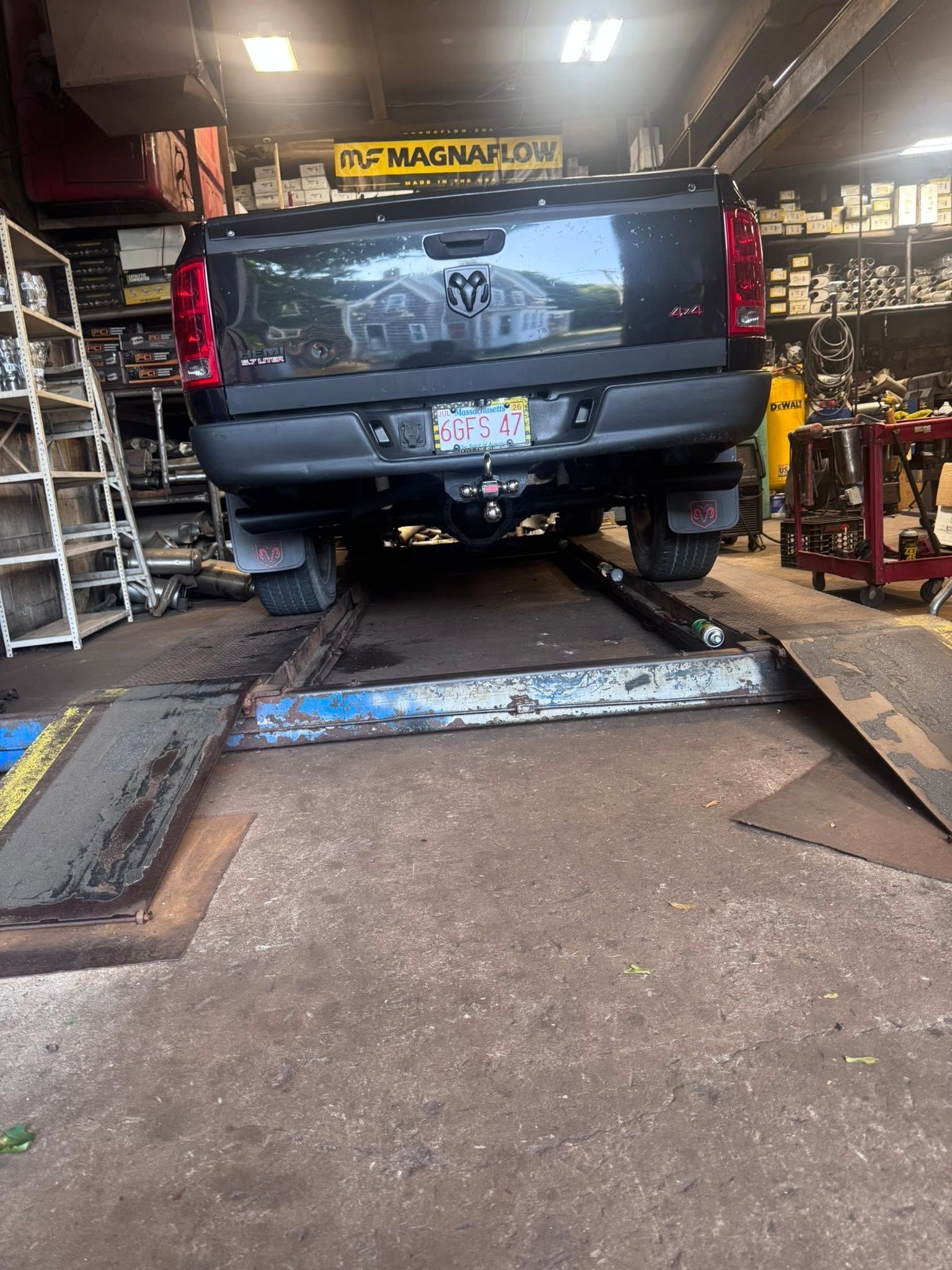 Black pickup truck on a lift inside an auto repair shop with tools and equipment around it