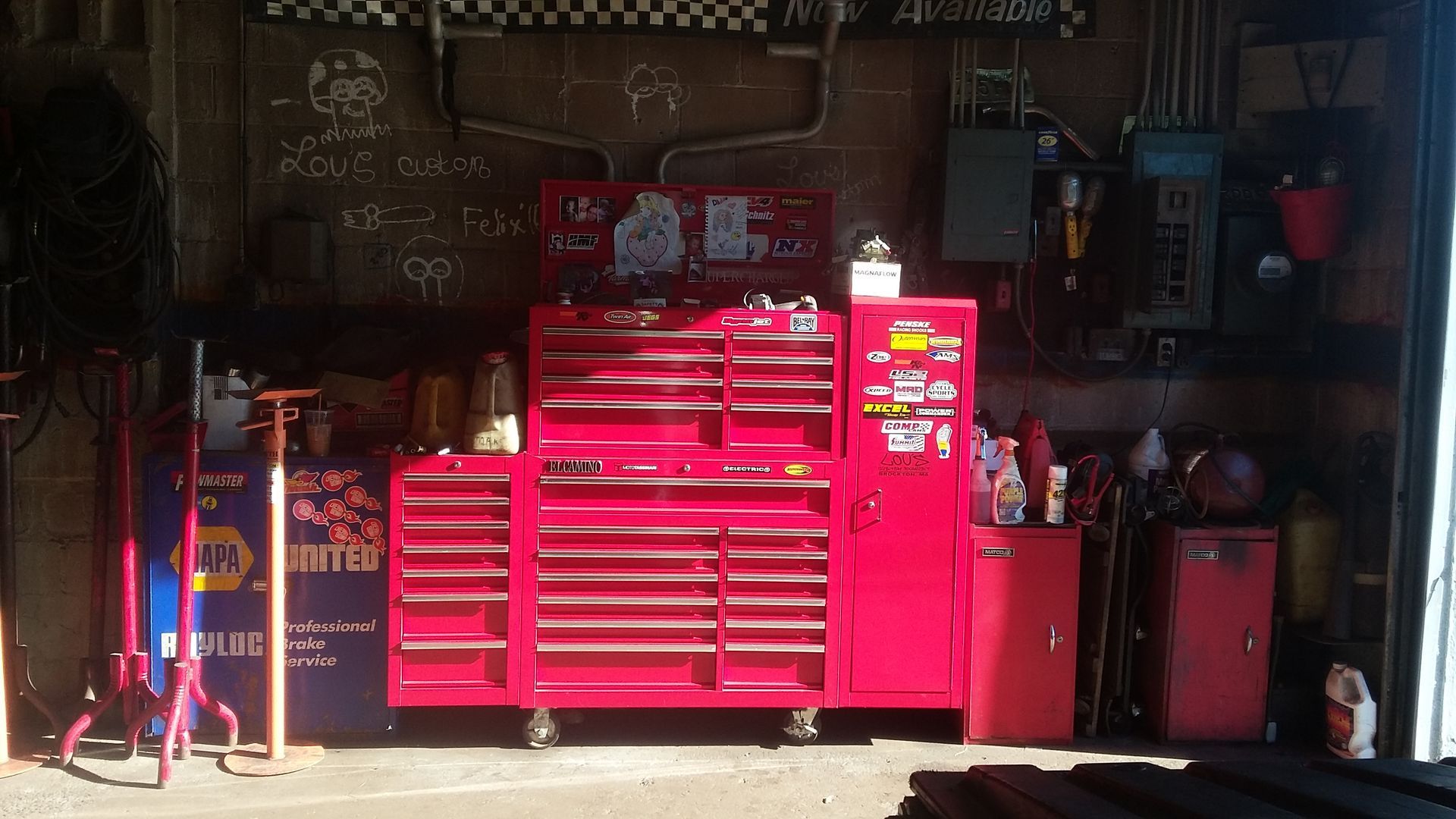 Bright pink rolling tool chests in a dim garage workshop with assorted tools and equipment.