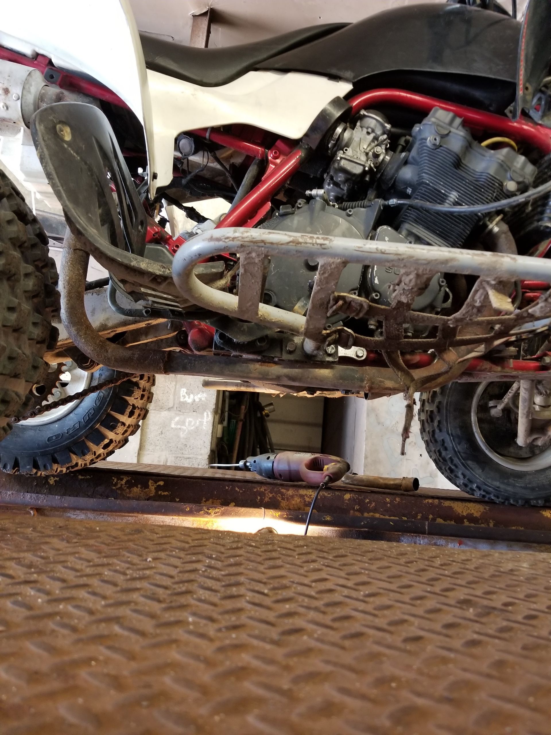 Red dirt bike on a metal ramp, side view with engine and frame visible.