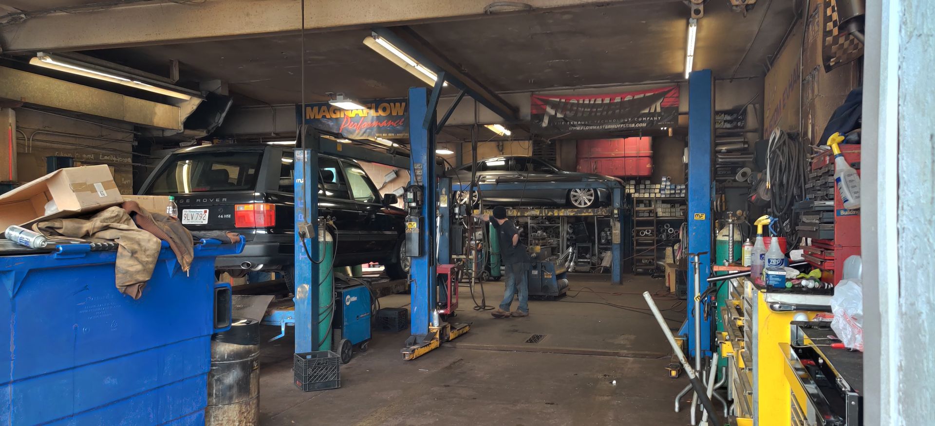 Auto repair garage with multiple blue car lifts, tools, and equipment in a cluttered workshop