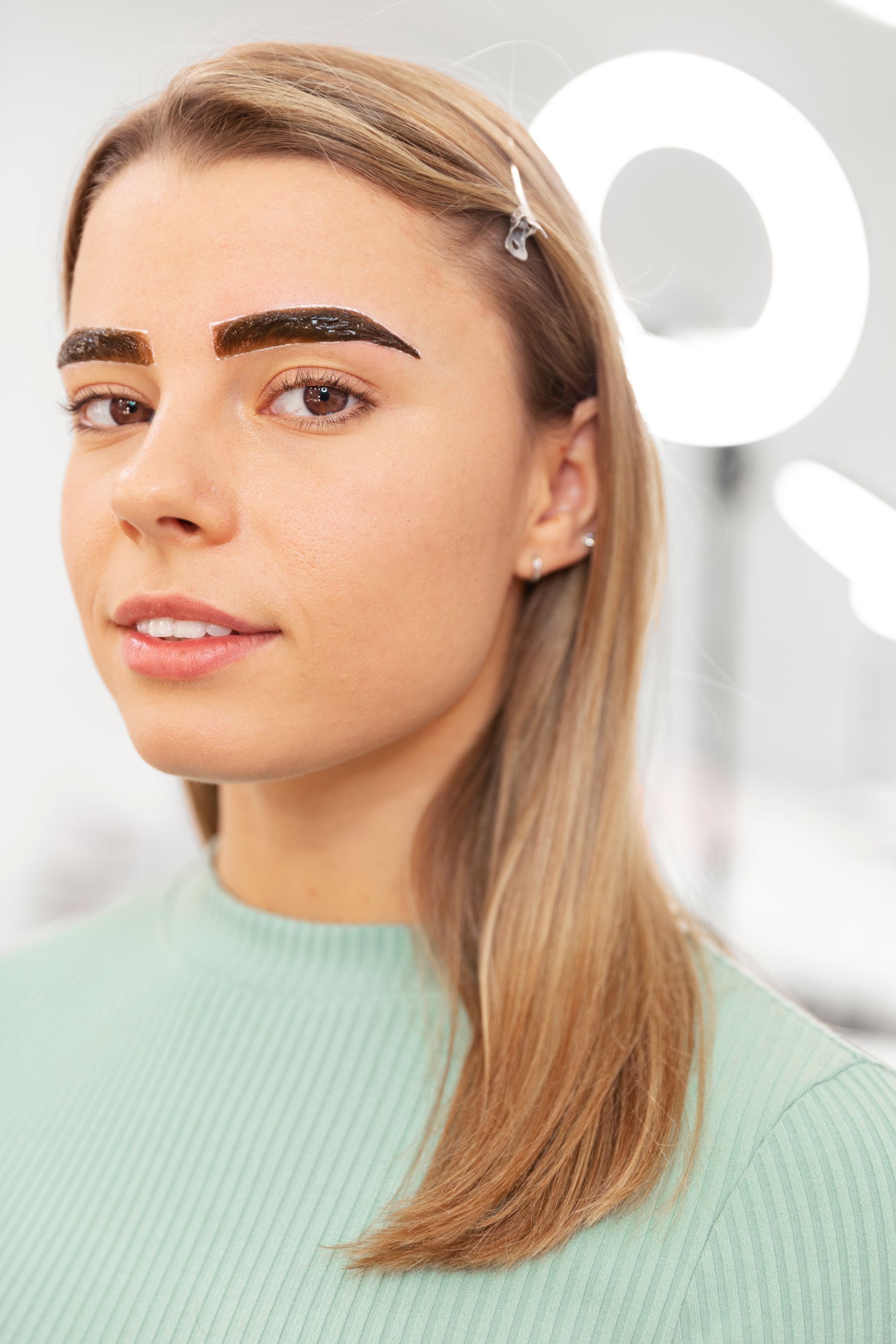 A woman is getting her eyebrows painted in a salon.