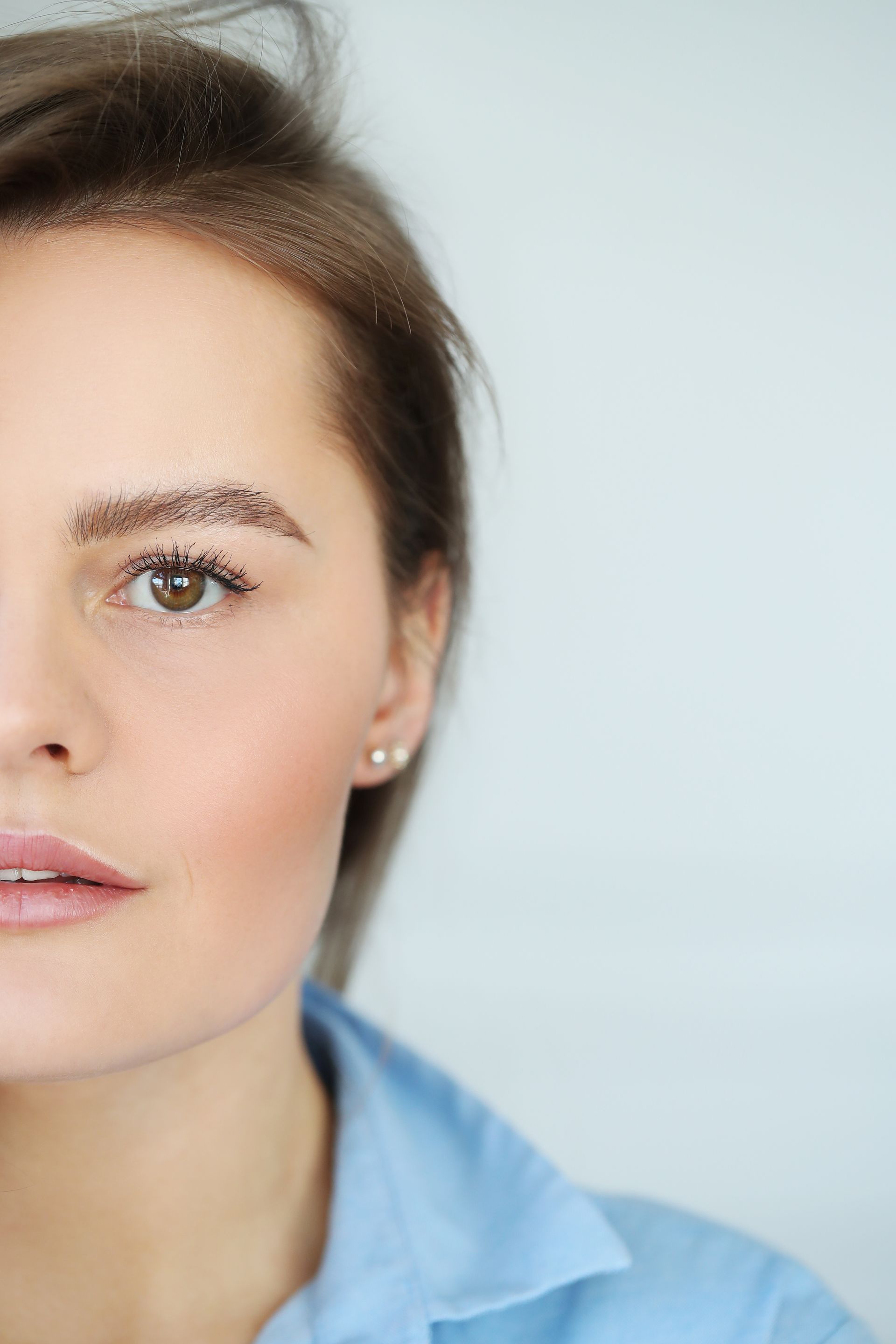 A close up of a woman 's face wearing a blue shirt and earrings.