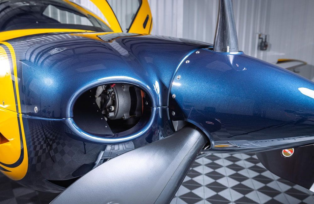 A blue and yellow airplane is parked in a garage.