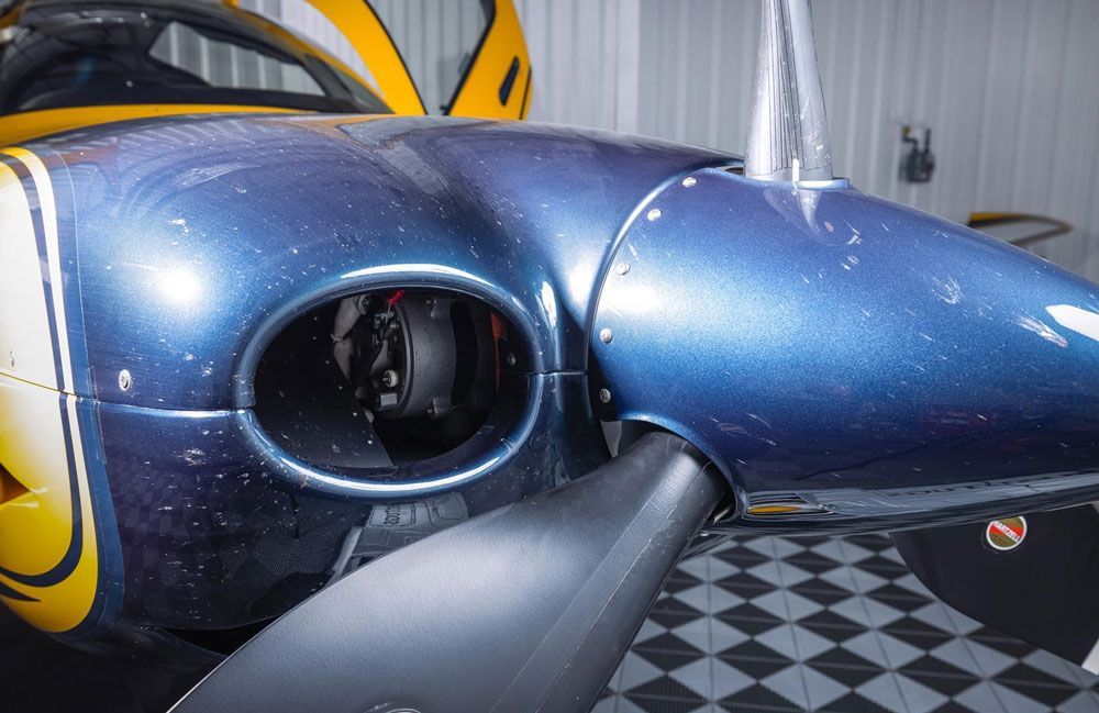 A blue and yellow airplane is parked in a garage.