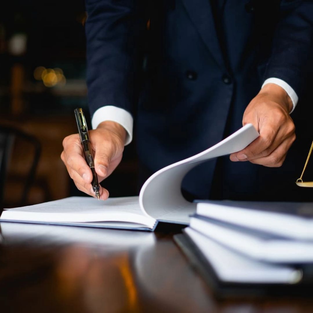 A man in a suit is writing in a notebook with a pen