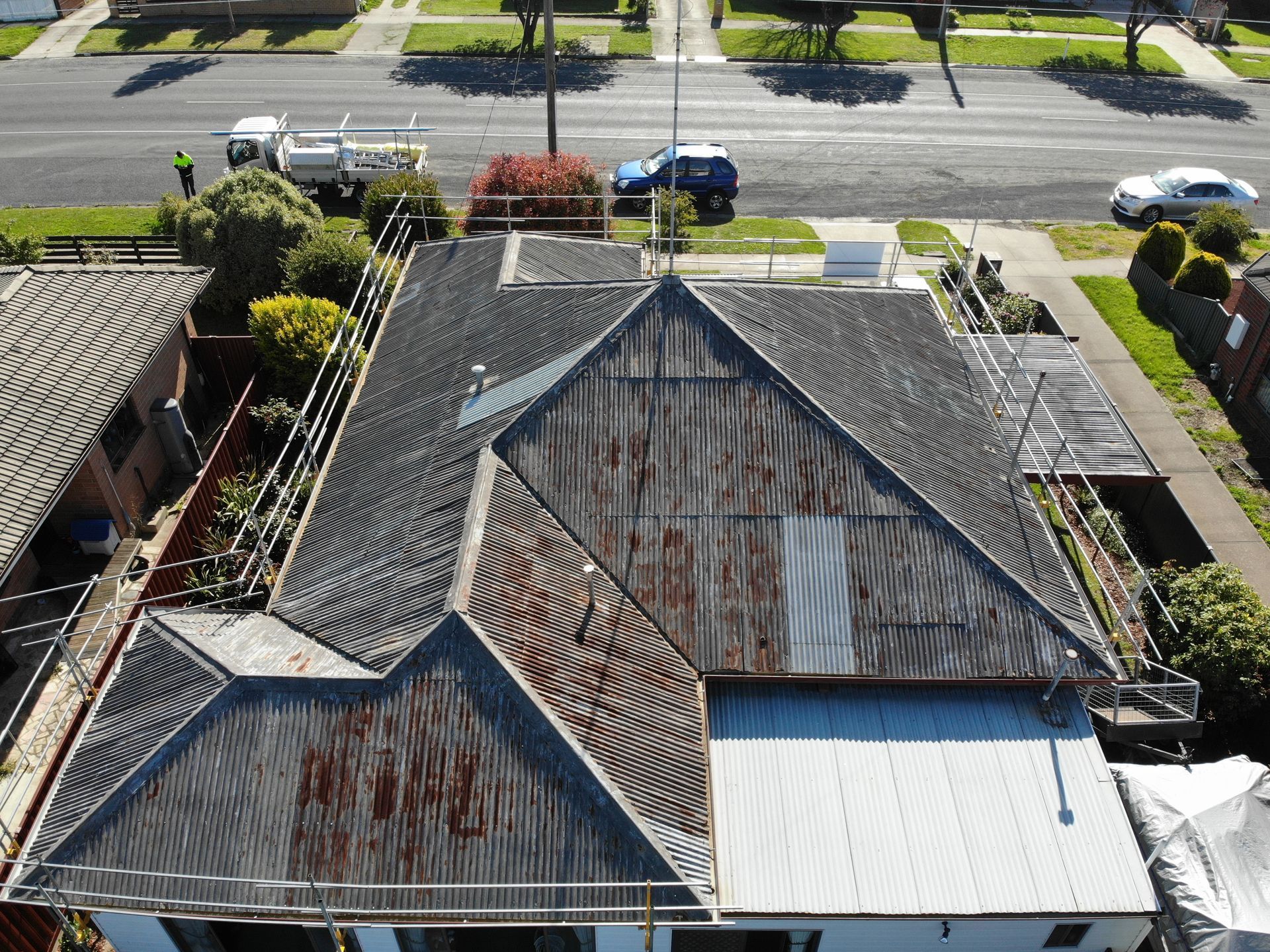 Before, rusted corrugated metal roof on a long single-storey weatherboard home with scaffolding, Wendouree VIC.