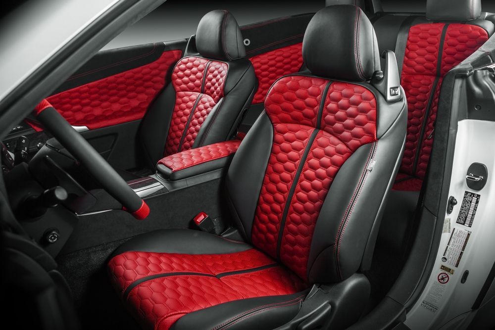 Car interior with black and red diamond-stitched leather bucket seats and matching red door panel accents.