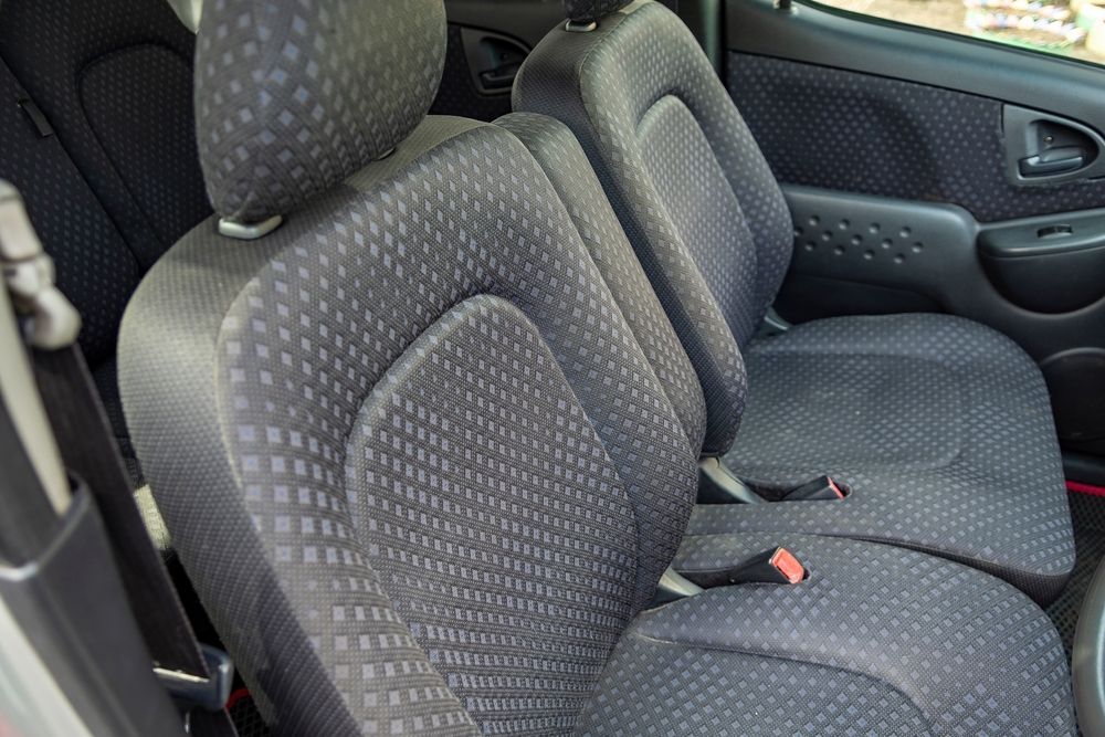 A pair of grey upholstered car seats with a textured, repeating diamond pattern, shown from an elevated interior angle.