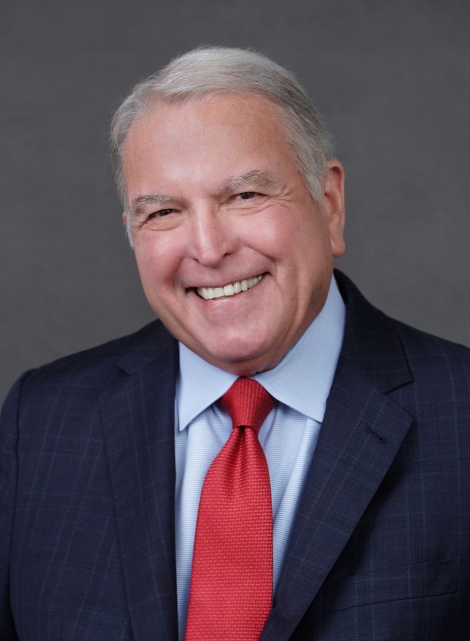 A man in a suit and tie is smiling for the camera