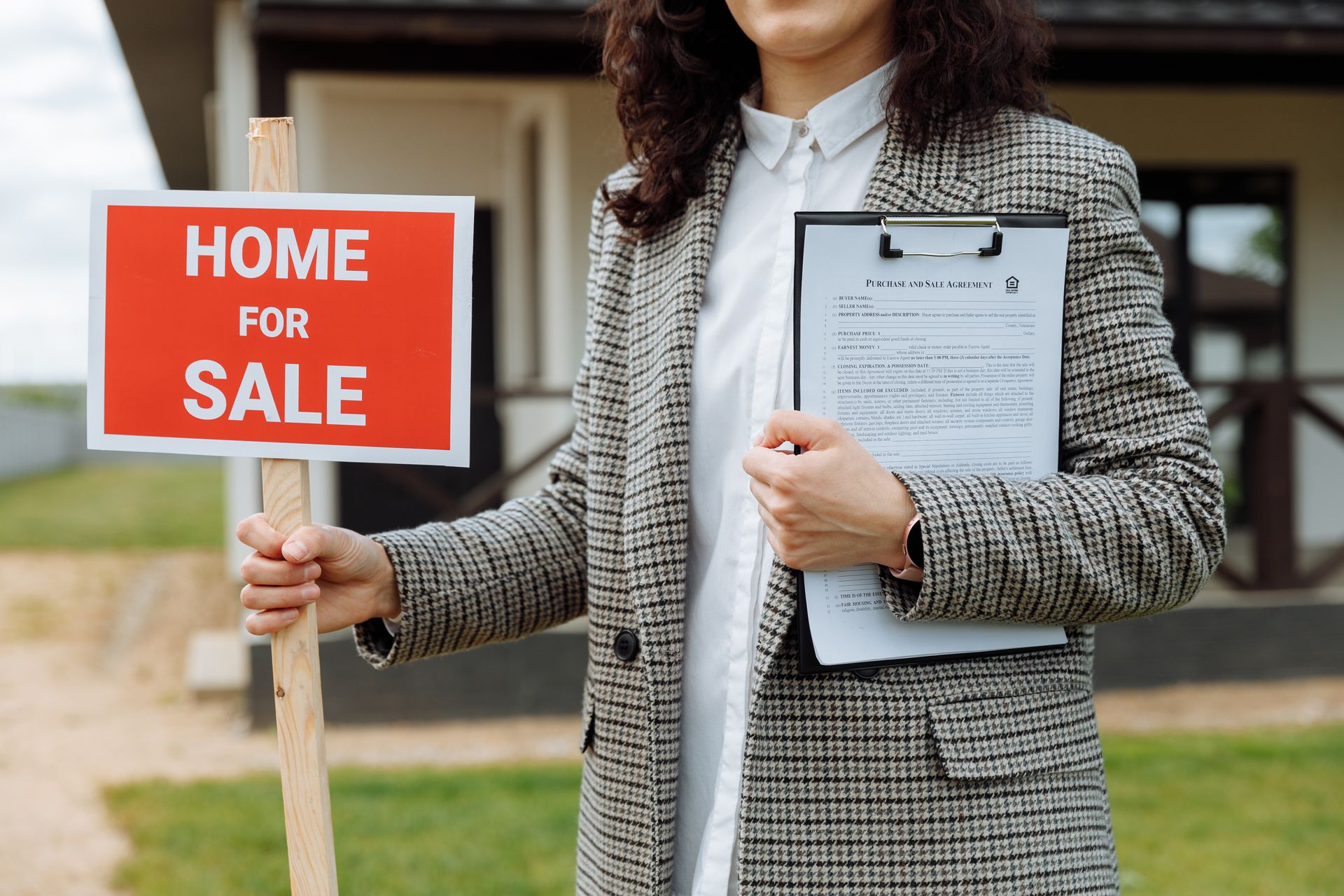 A woman is holding a home for sale sign and a clipboard.