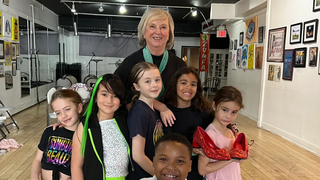 Group of children with an adult woman smiling in an art gallery hallway