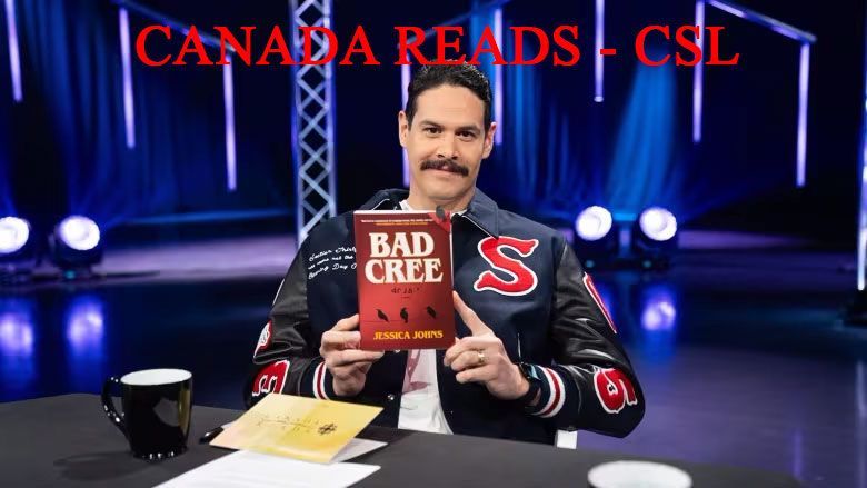 A man sitting at a table holding a book titled bad cree