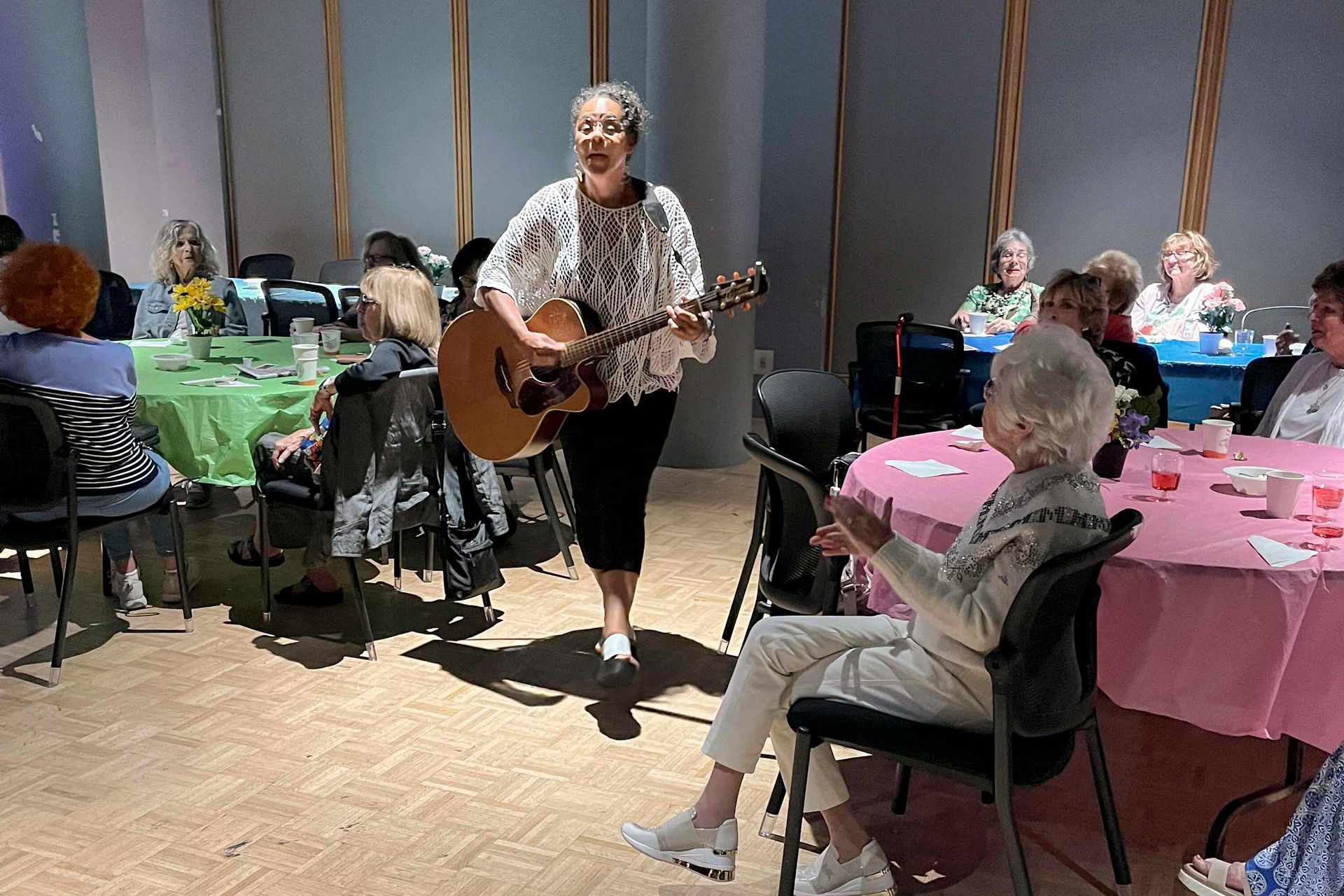 A woman is playing a guitar in front of a group of people
