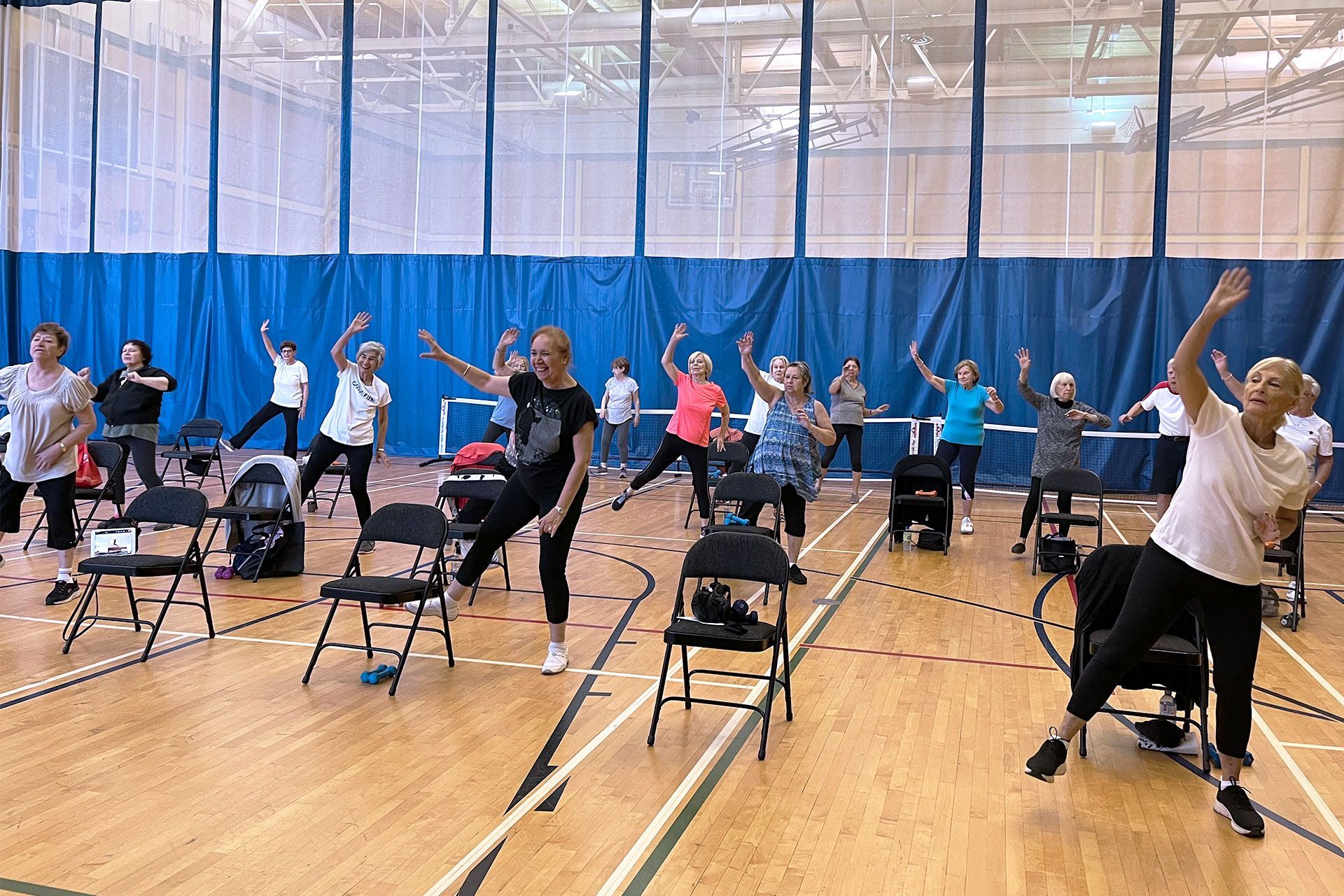 Women exercising with chairs in a gym.