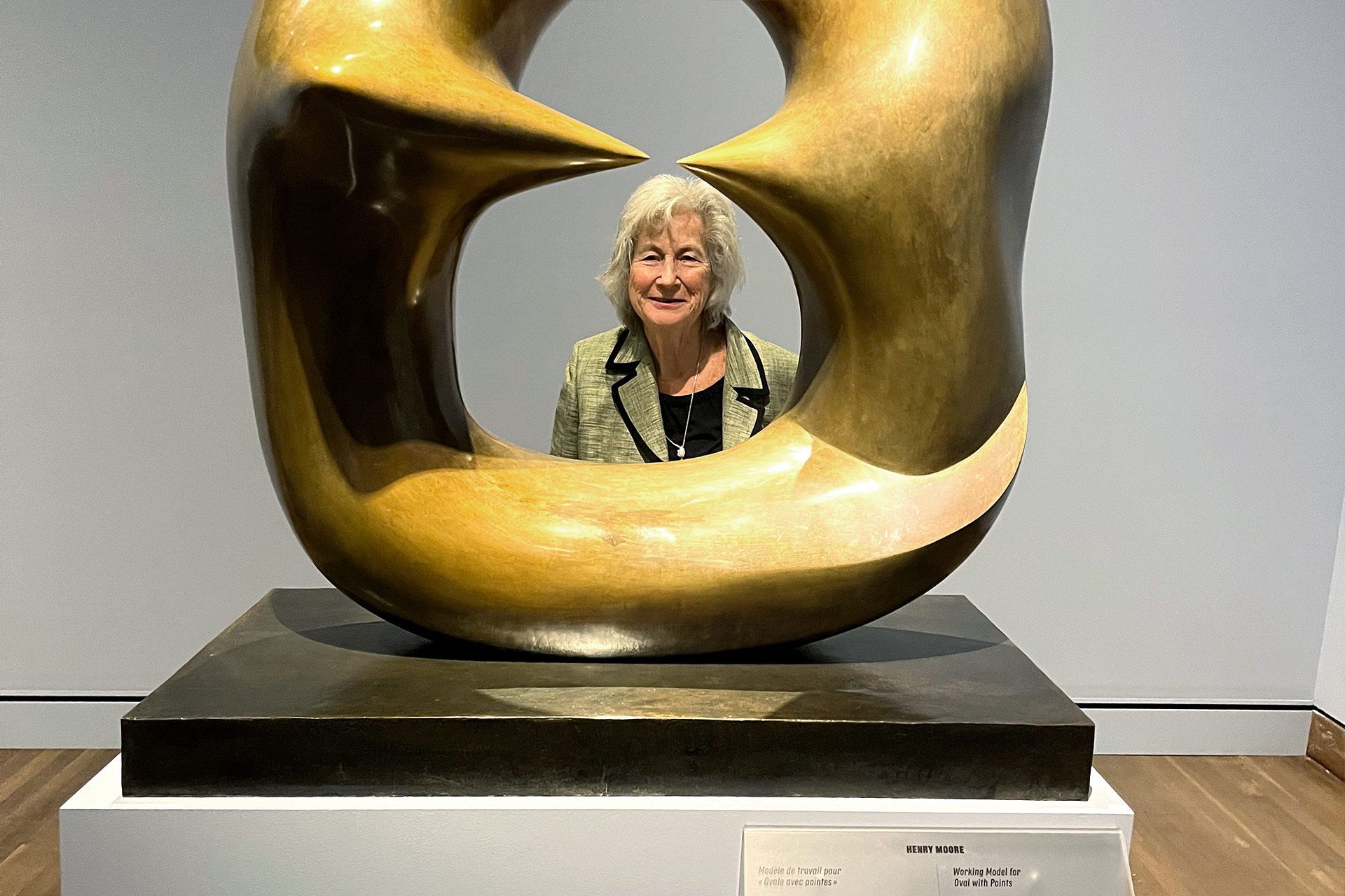 A woman stands in front of a large gold sculpture