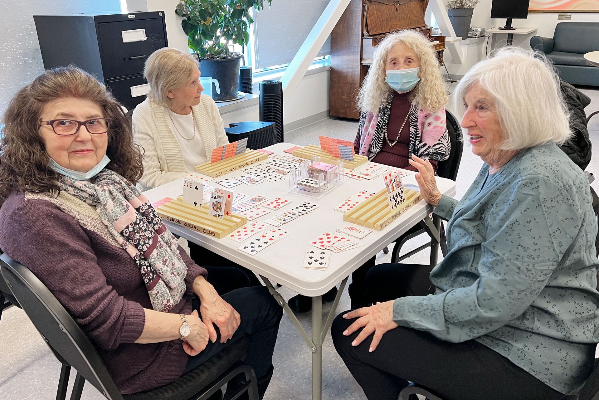Women sitting at a table playng a card game.