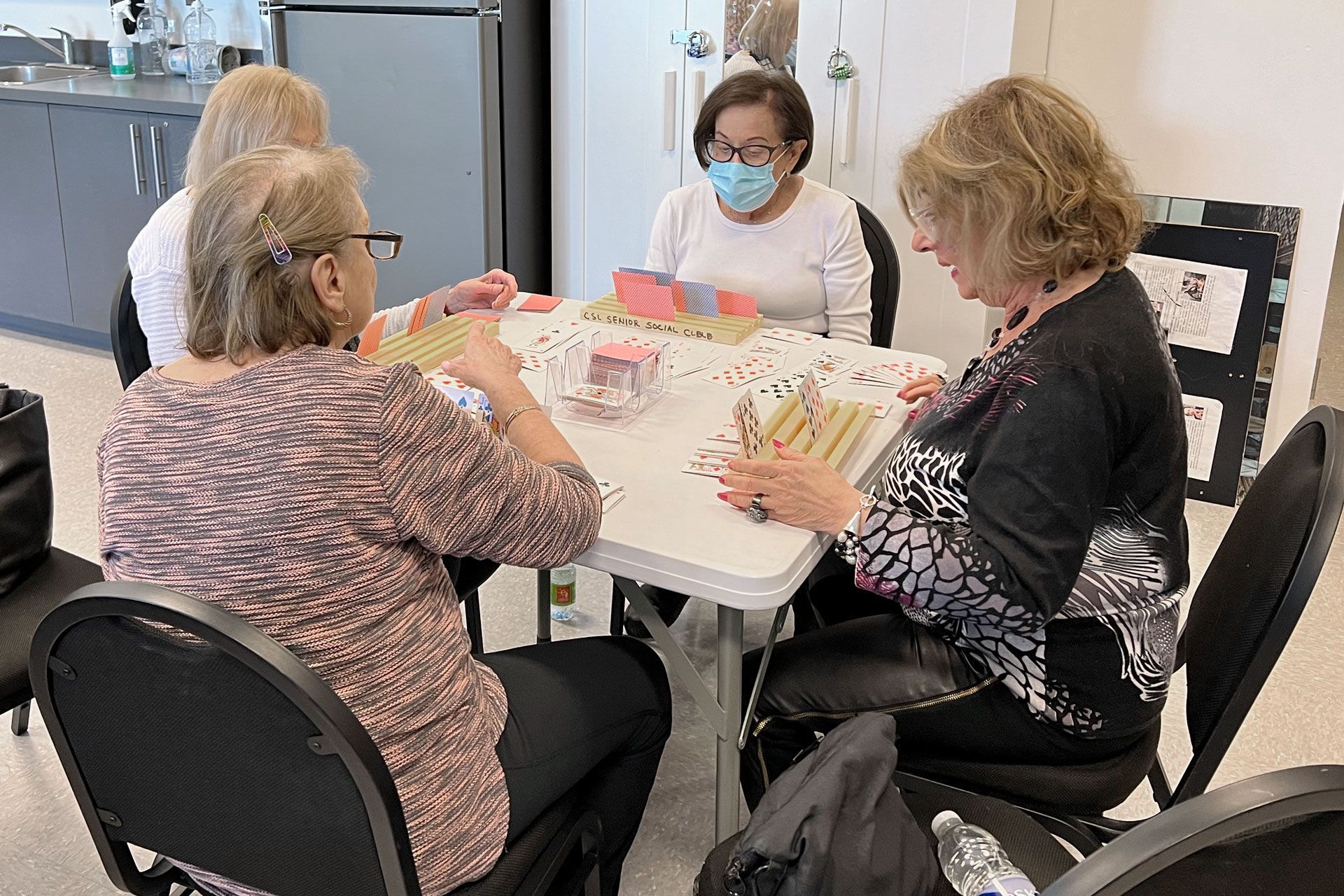 A group of women sitting around a table with the word Samba Canasta on the bottom