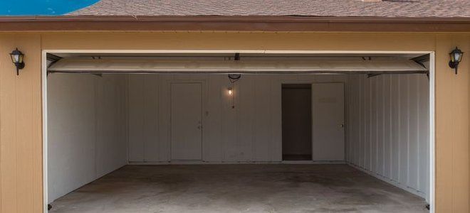 An empty garage with the door open and a doorway. An empty garage with the door open and a doorway.