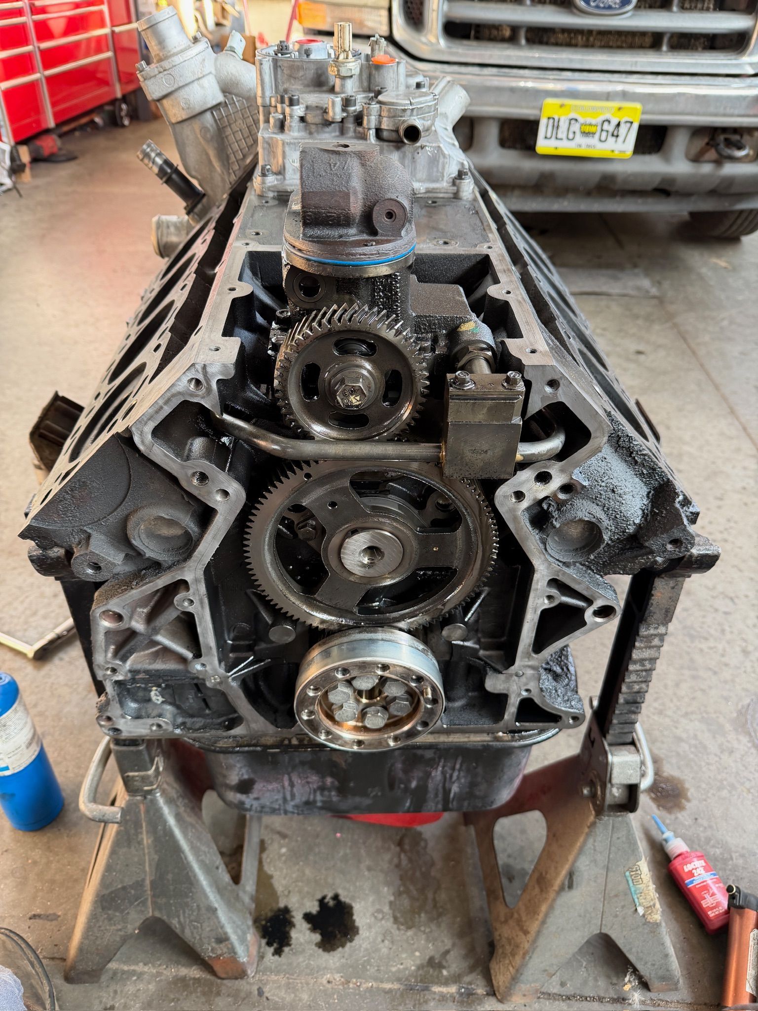 Open car engine block on a workbench in a garage, with visible gears and metal parts.