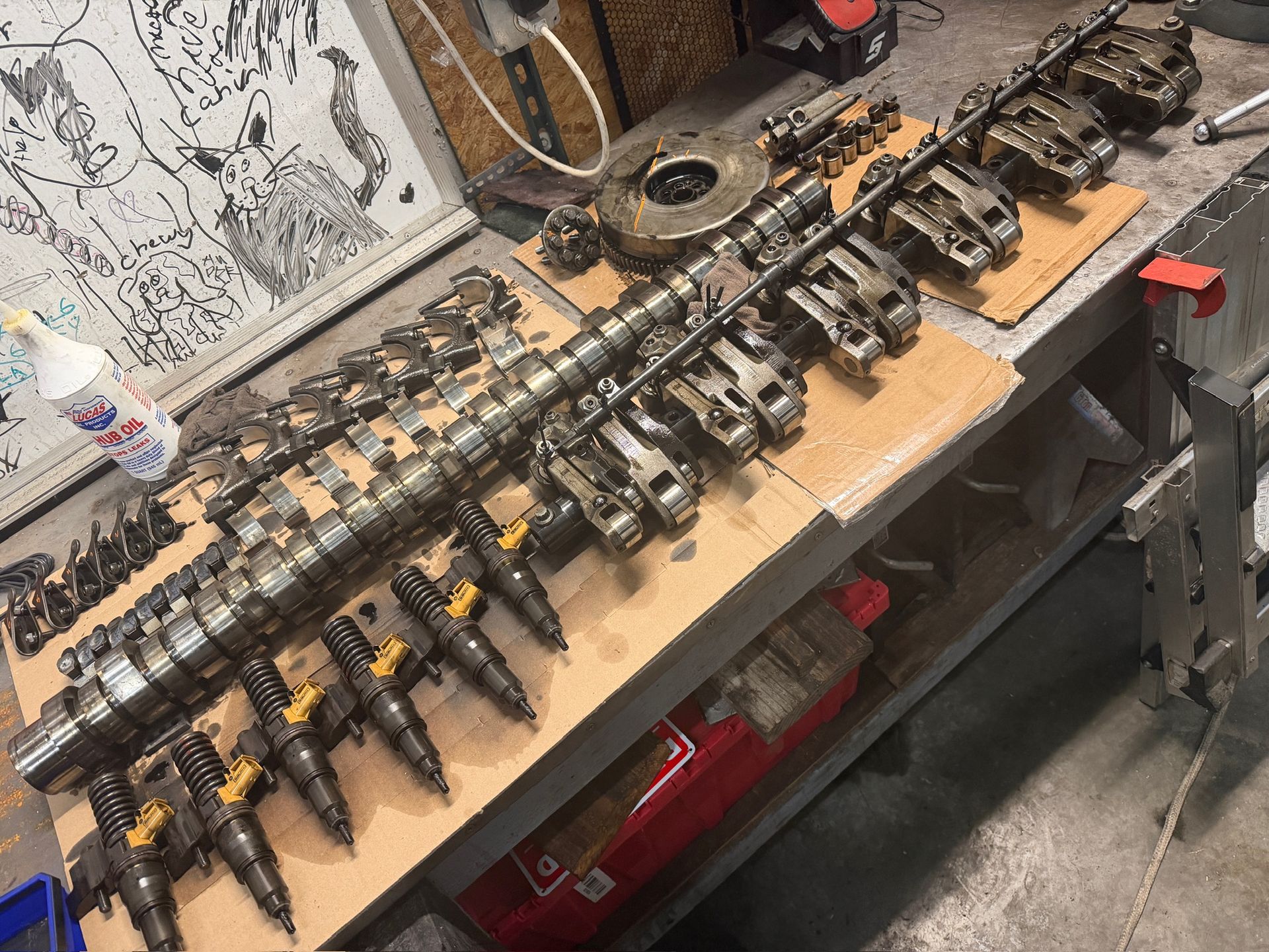 Workbench with a row of dark mechanical parts and tools laid out on a wooden table.