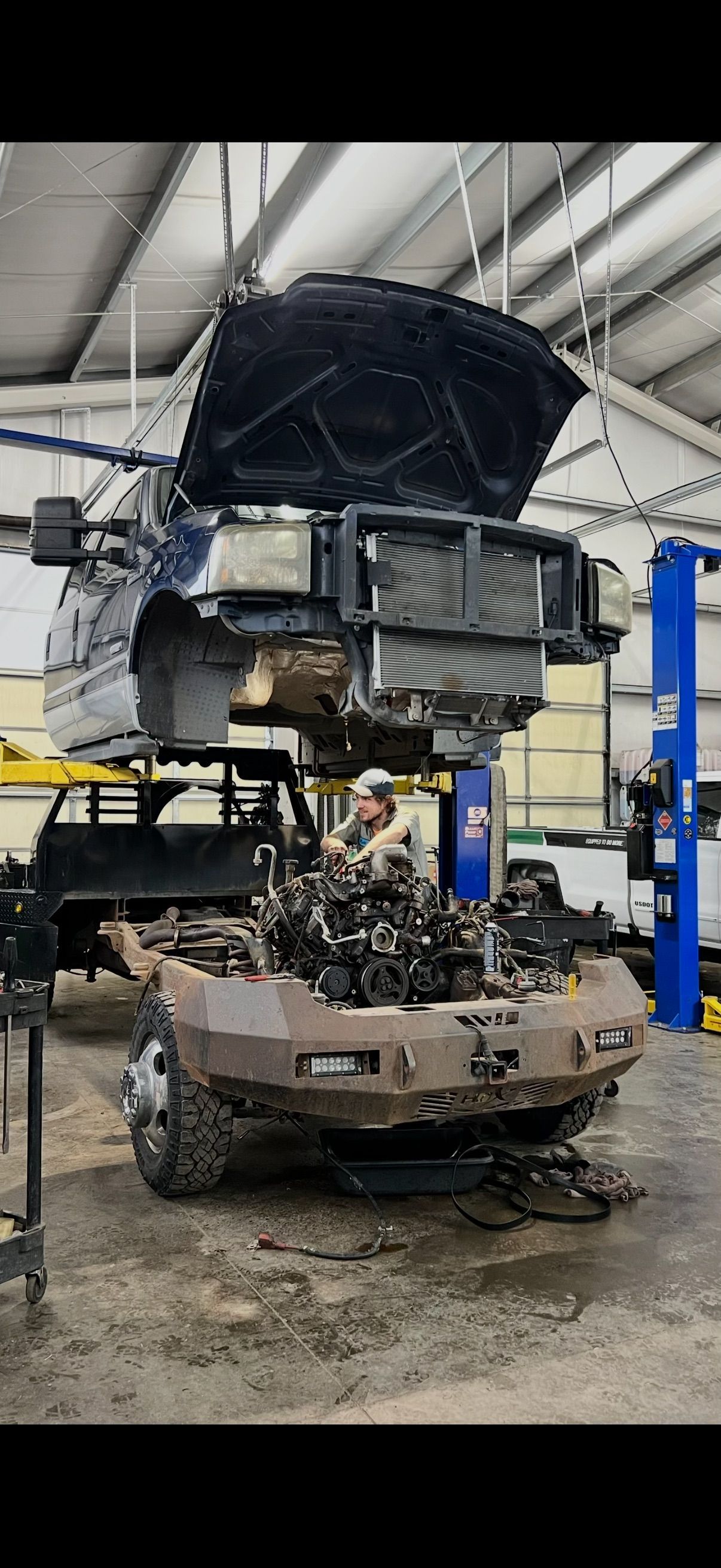 Damaged car in a repair shop, hood open with front end disassembled and engine exposed