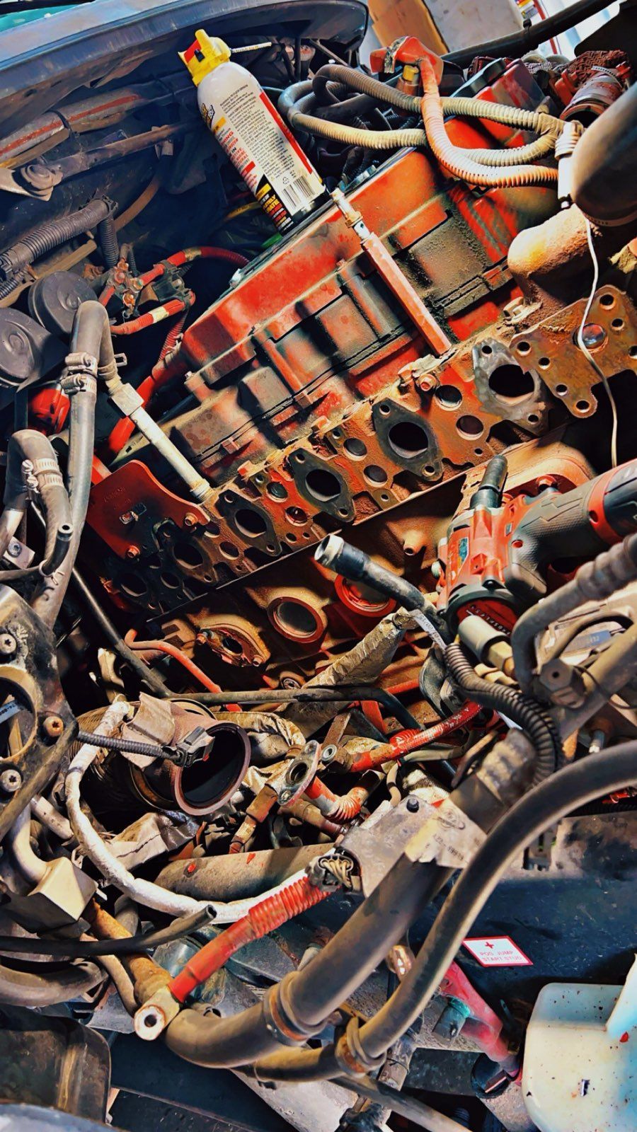 Close-up of tangled metal parts and tools in a cluttered workshop, with red and silver components.
