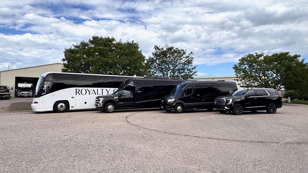 White and black passenger vans parked outside a building under a partly cloudy sky