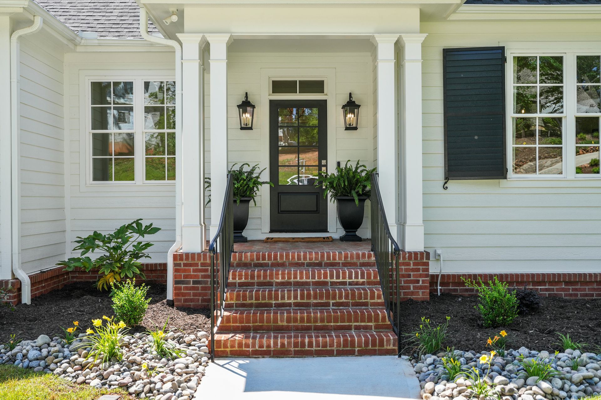 A white house with a black door and brick steps